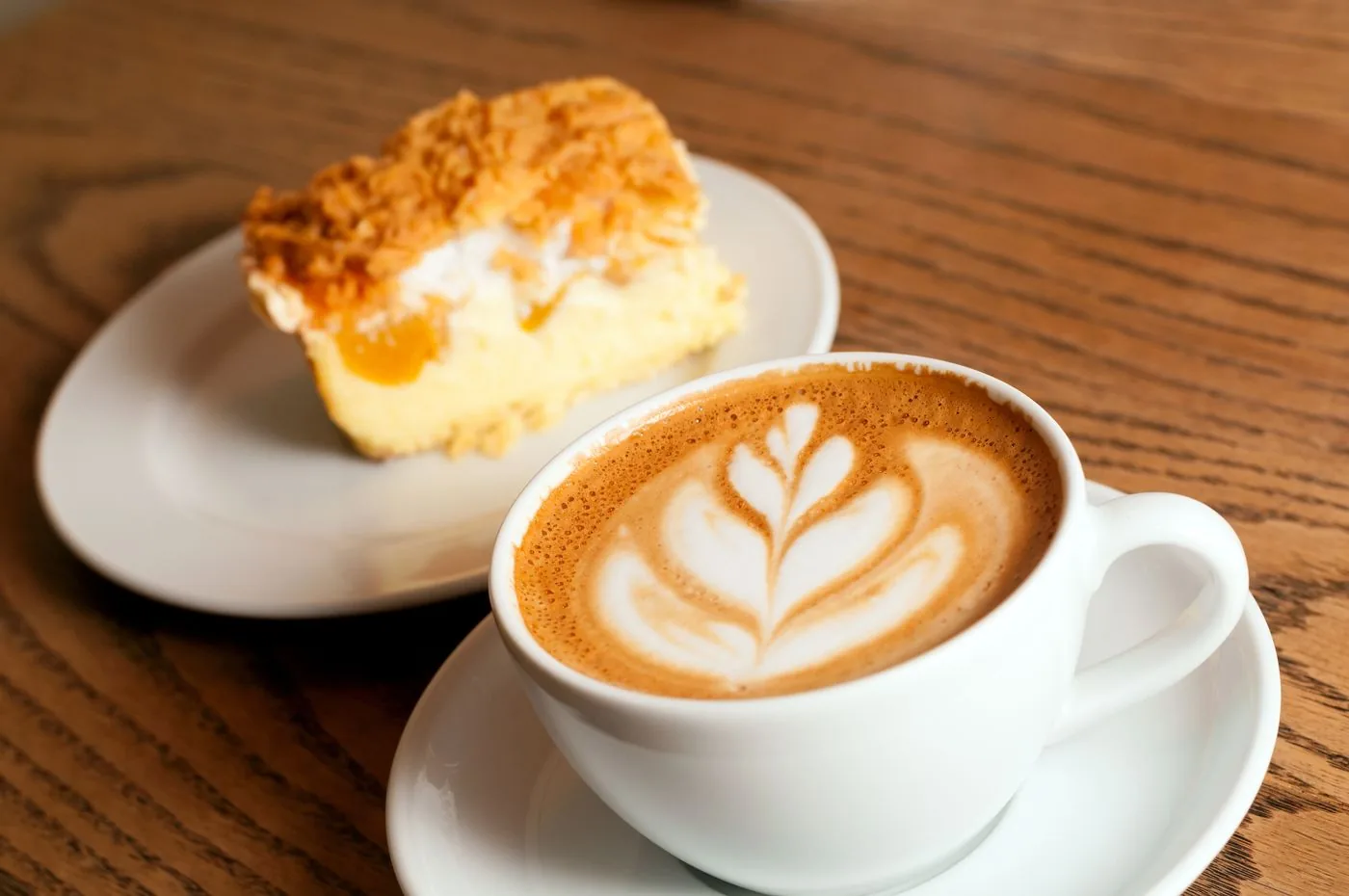 Cappuccino mit Latte-Art und ein Stück Kuchen