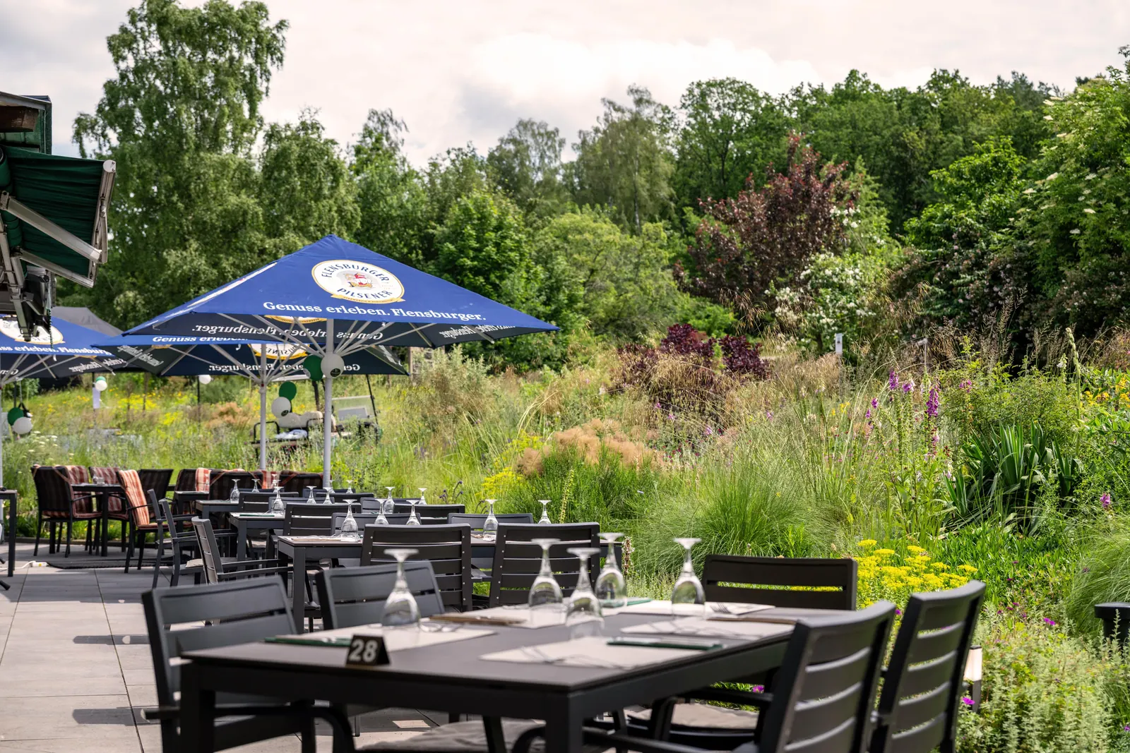 Terrasse mit Sonnenschirmen am blühenden Staudengarten